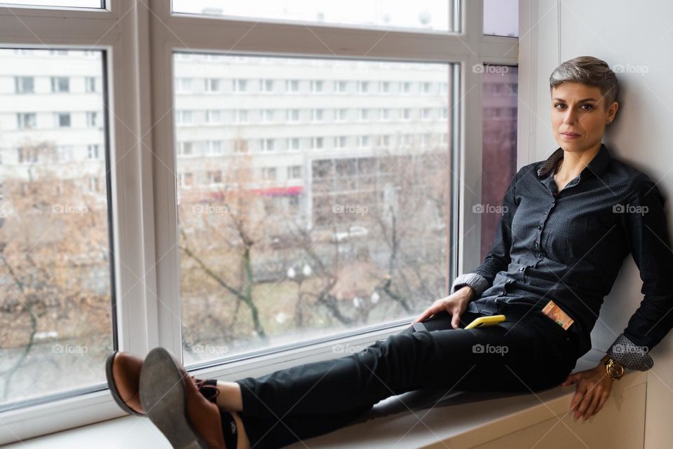 Beautiful woman sitting on the windowsill 