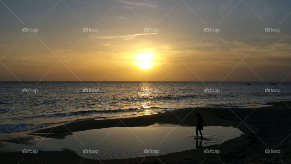 Child playing in the water at the sunset