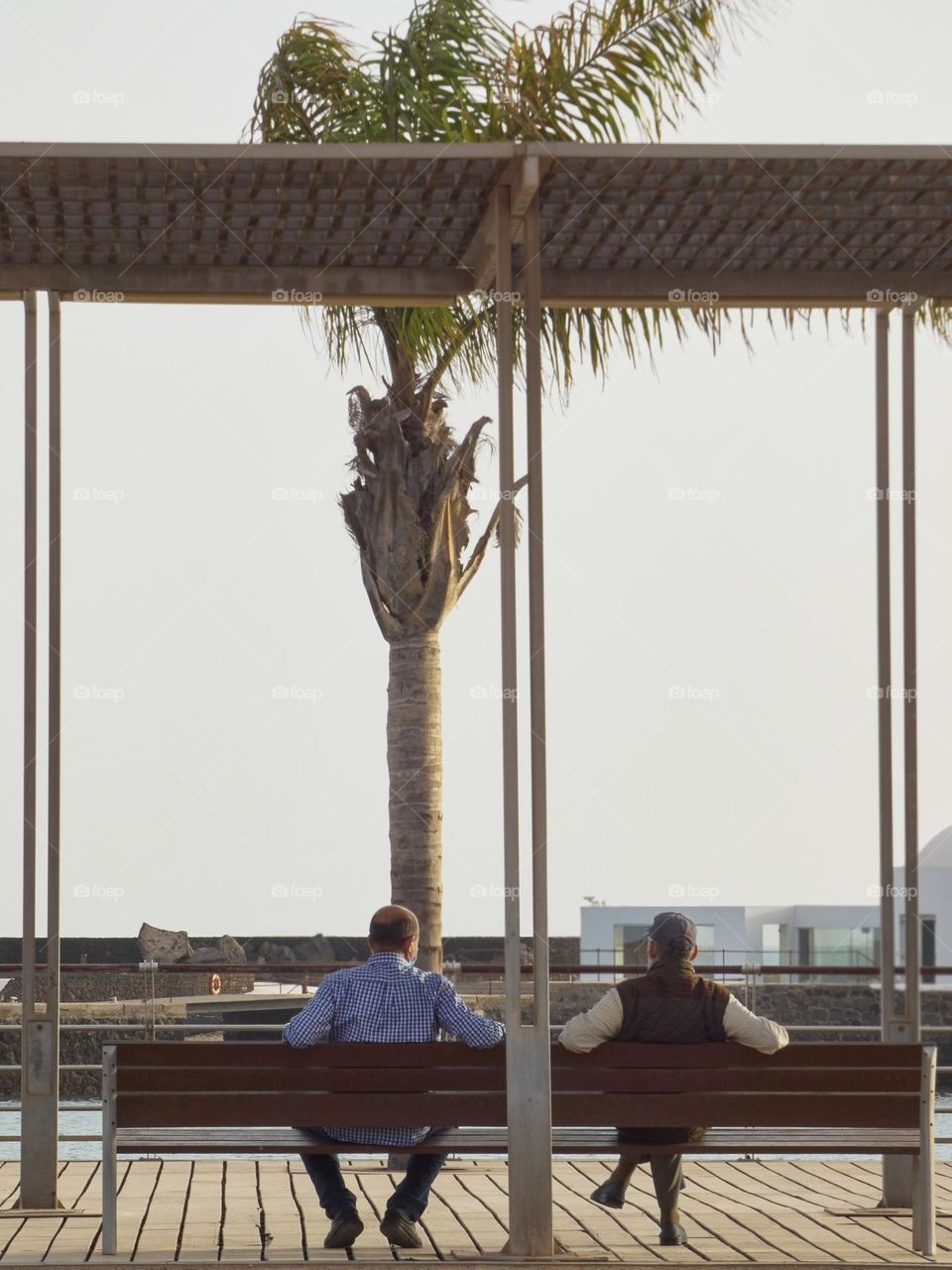 retired people talking on a bench sitting with a view of the sea