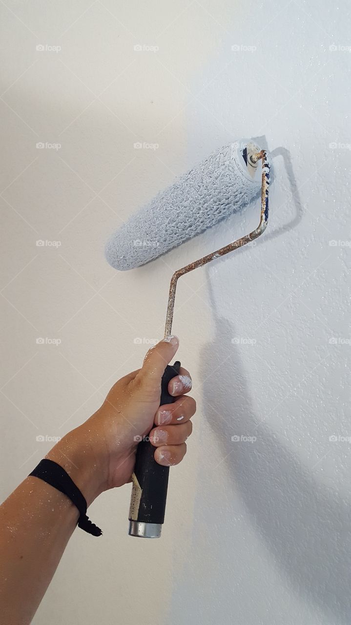 using a roller to paint the wall