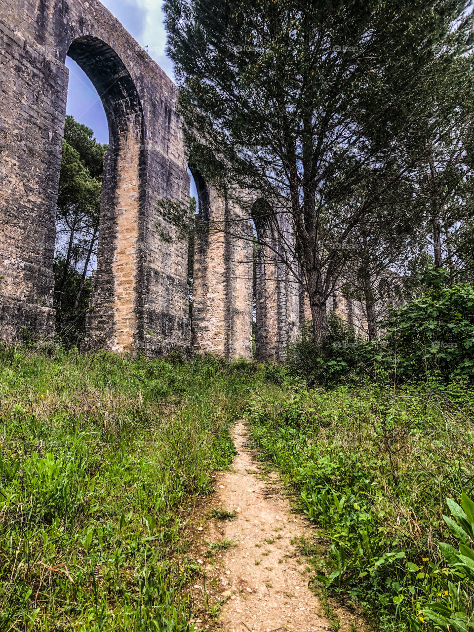 A trails leads up next to a section of the 6 kilometre aqueduct of the Convento de Cristo built 1593-1614, Tomar, Portugal 2021
