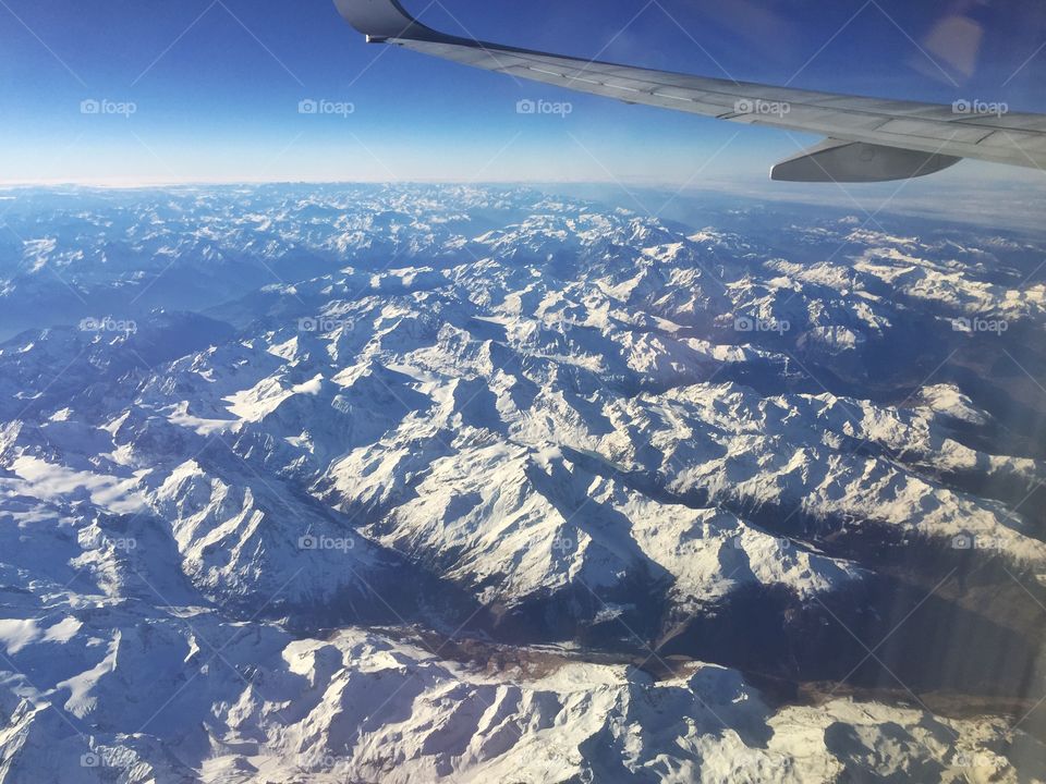 The tops of the snowy Dolomites seen from the window of the plane during a travel in Europe in winter