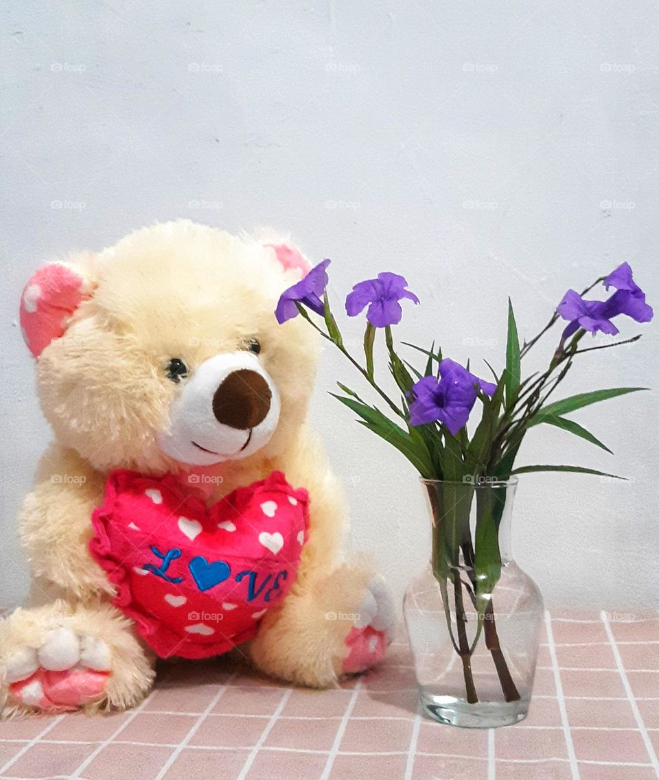 Cute teddy bear and beautiful purple colour of flowers in vase. Bright and colourful flowers