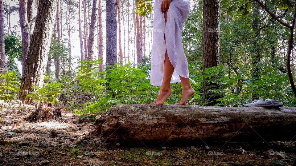 Woman walking on tree trunk in forest