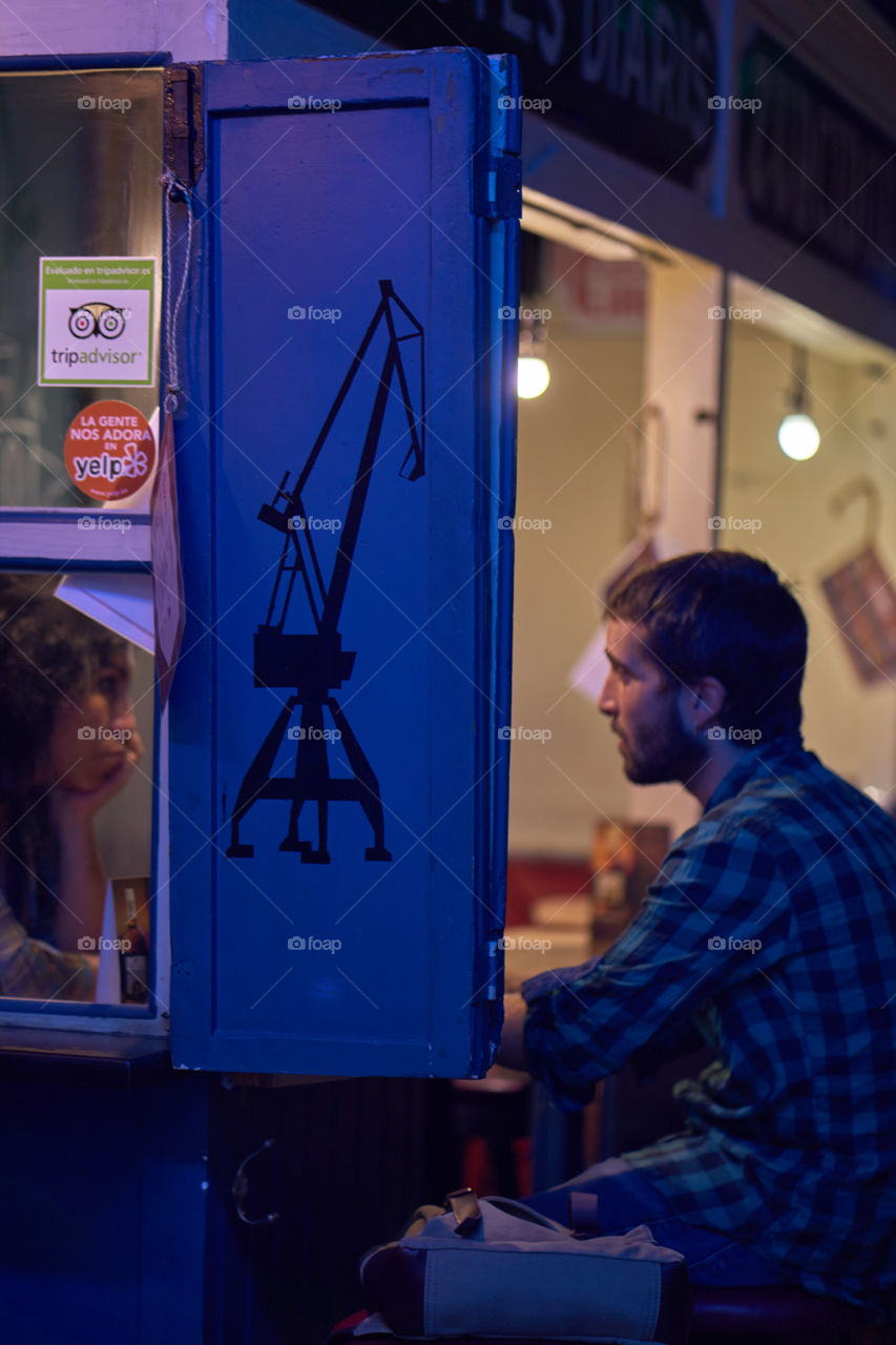 Couple one in front of the other sitting in a bar