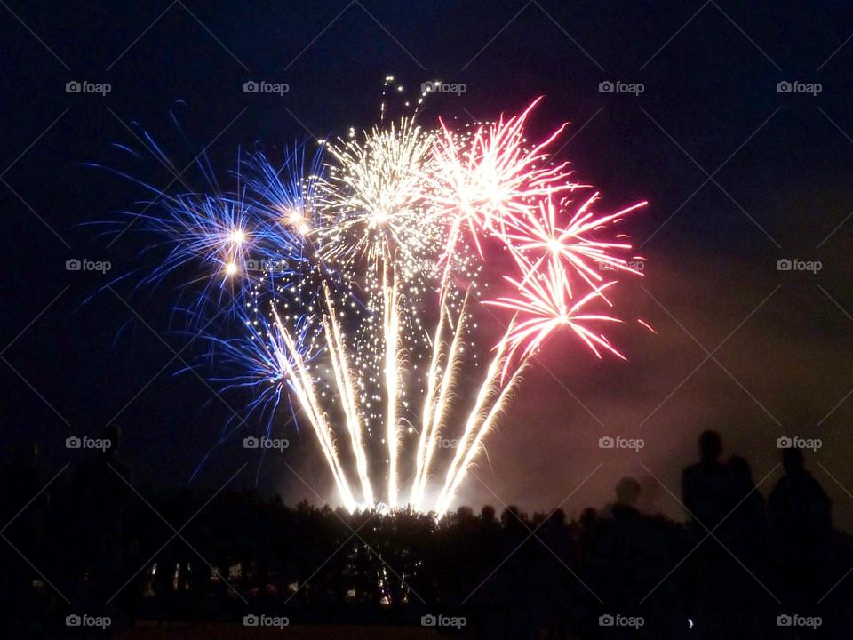 In France, the July 14 firework celebrates the national day and bring the French together around festivities. This photograph was taken in 2023 in a small town, the colors Blue White Red are those of the national flag.