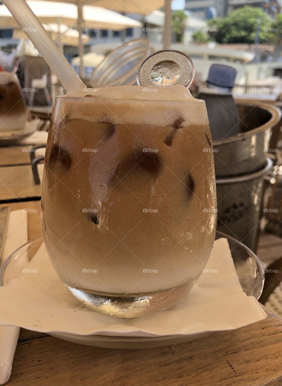 A brown and white Ice coffee with ice cubes
