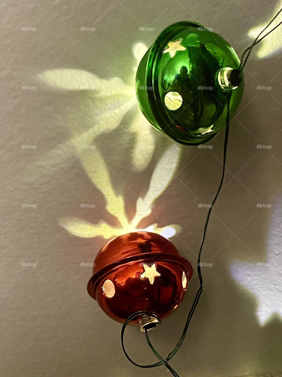 Red and green Christmas bell lights making reflections on a wall