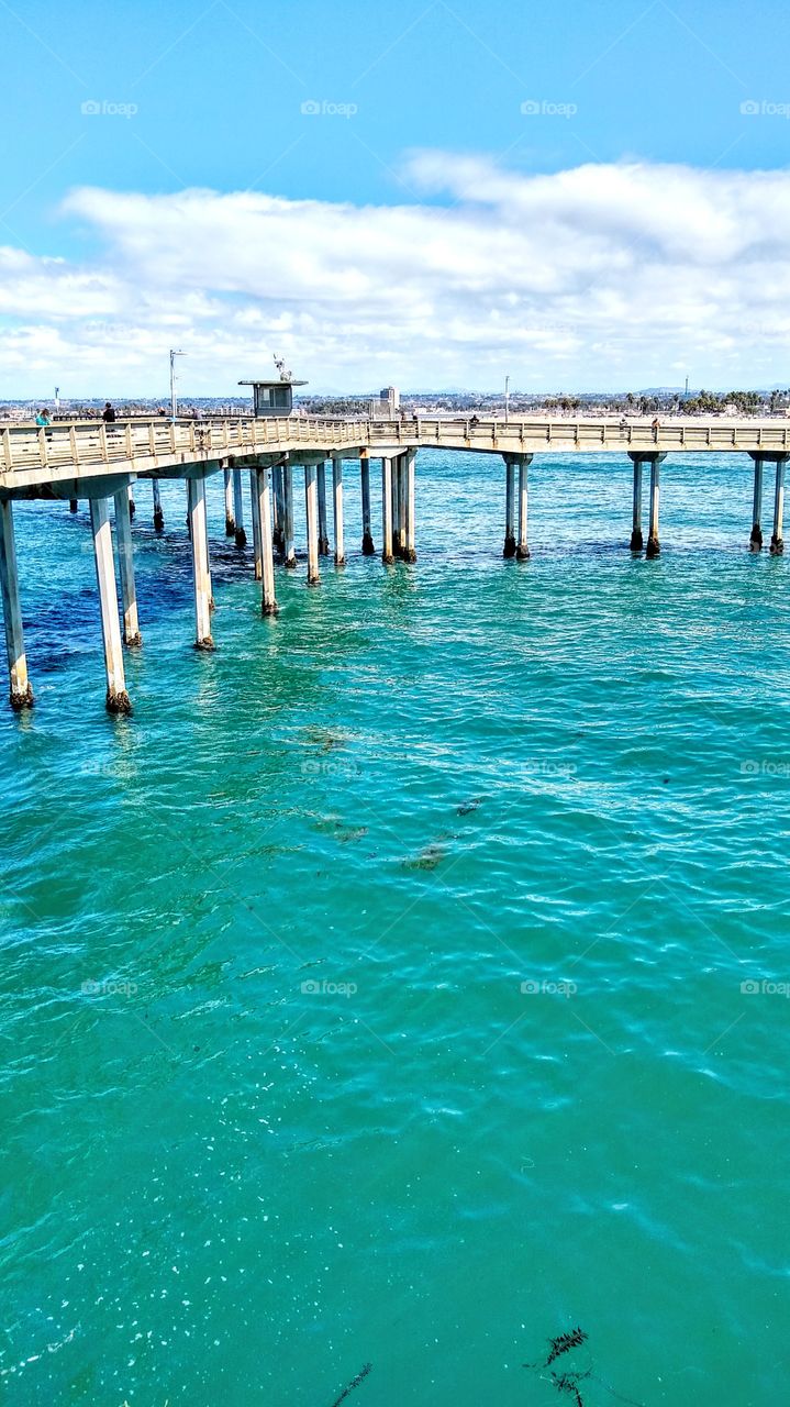 Pacific waters through pylons and railing of the Free People's Fishing Pier in Ocean Beach, CA.