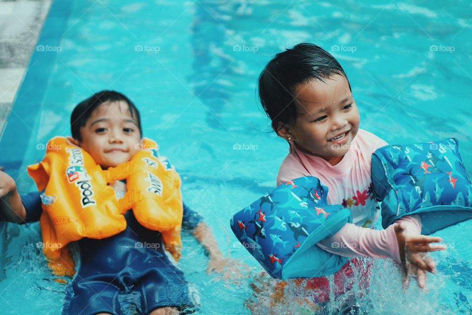 Little boy and girl swimming in the pool.
