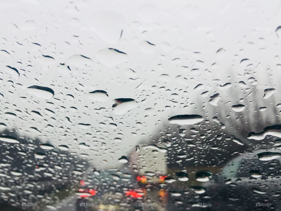 Raindrops on car windshield and traffic ahead 
