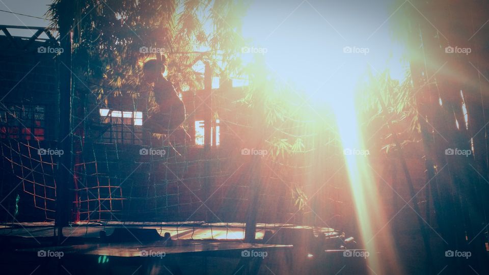 Criança em pula pula à luz do sol ao entardecer.