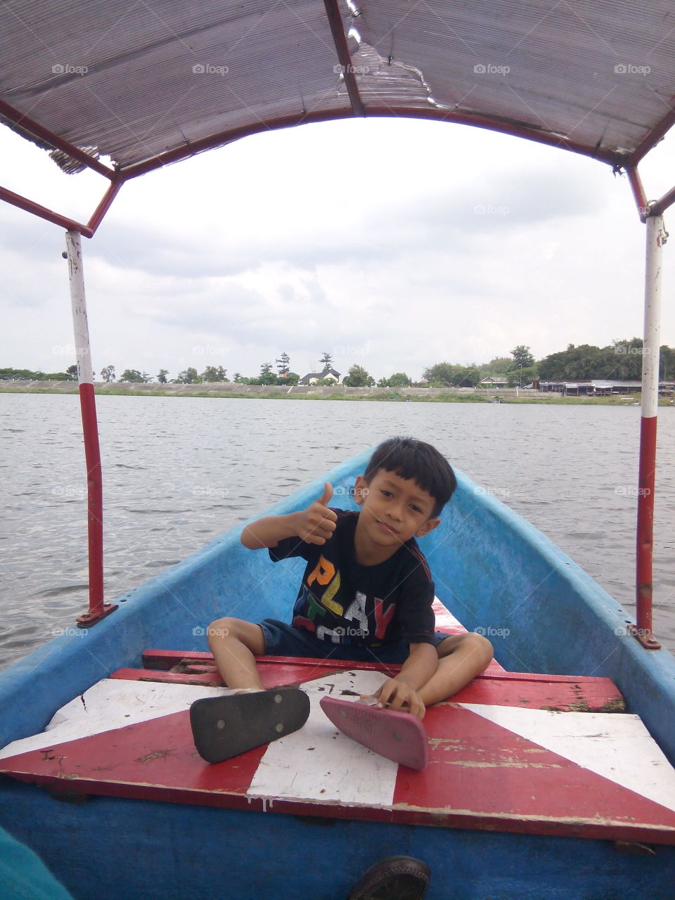 Little boy sitting on boat in lake