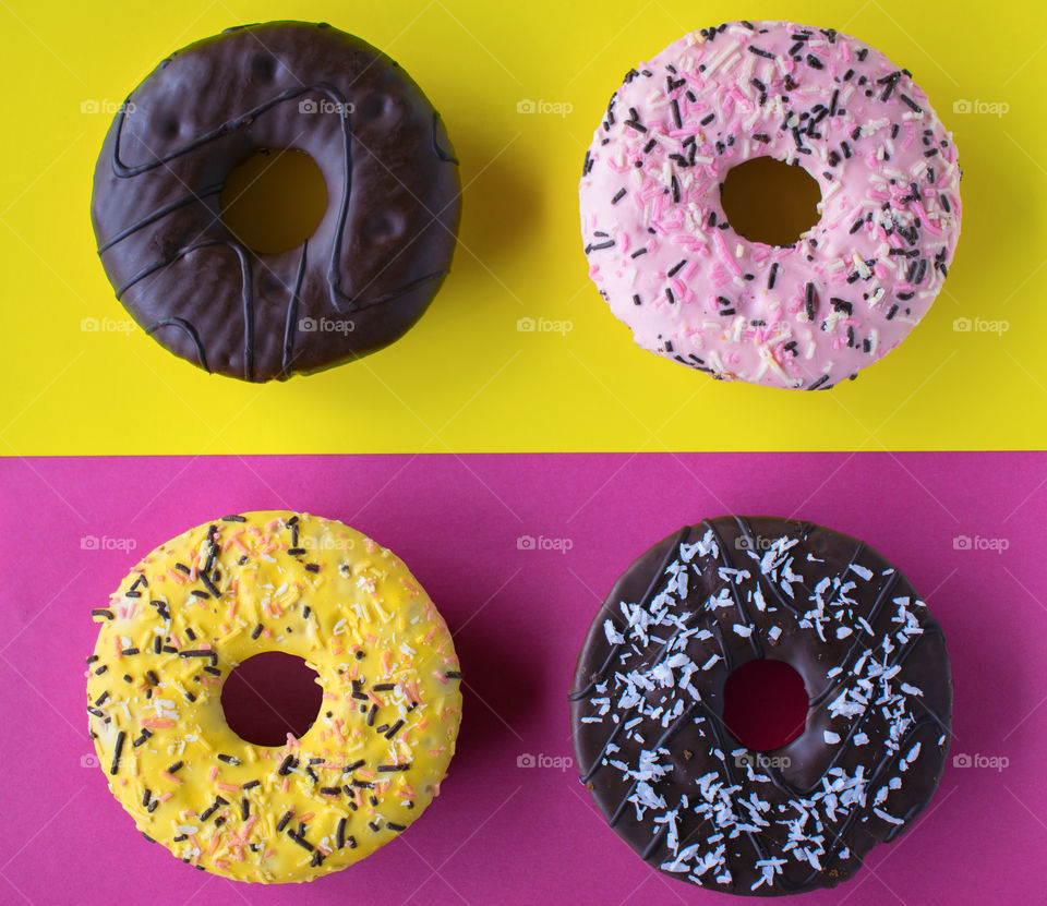 Sweet colourful donuts on pink and yellow background in pop art style