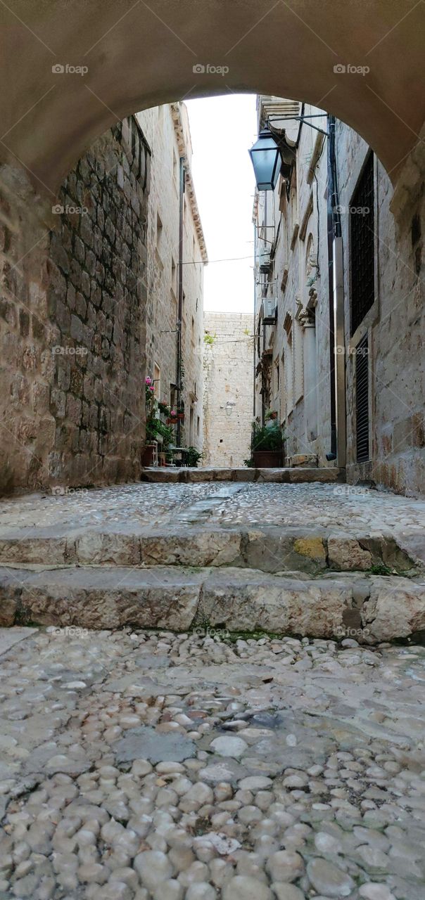 steps of old narrow street under arch