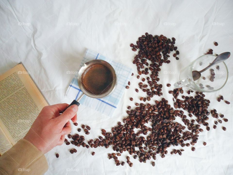 Turka for brewing coffee, a book, a cup with a spoon and coffee beans