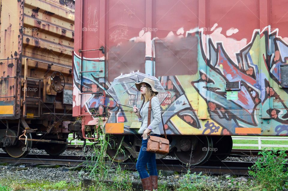 Woman standing in front of a train covered in graffiti 