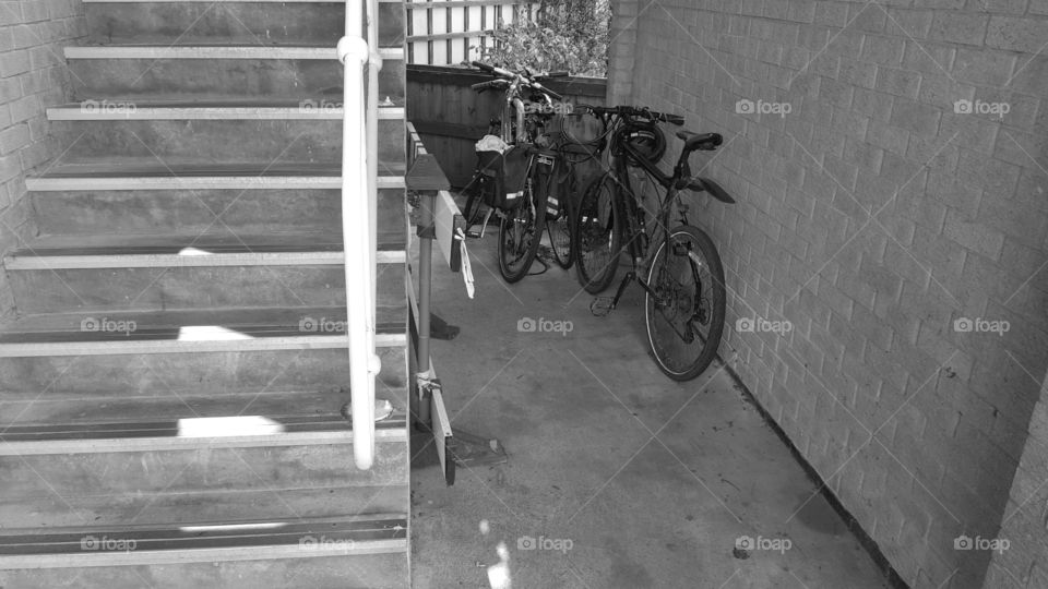 Bicycles under a stairwell greyscale