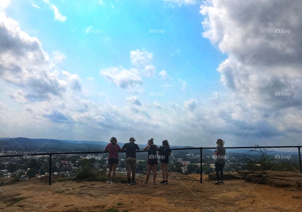 Friends standing on mountain and looking over city 