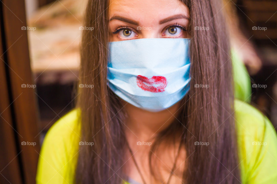 A young girl wearing a mask from the coronavirus pandemic, her lips are painted with red lipstick.