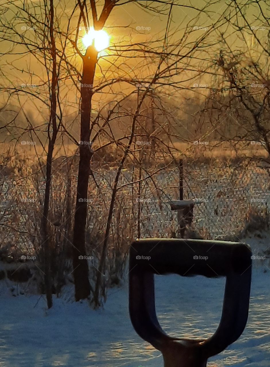 winter golden sunrise  with snow shovel handle glittering