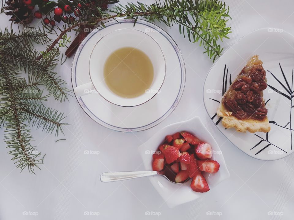 Cup of mint tea, bowl of strawberries and pecan pie
