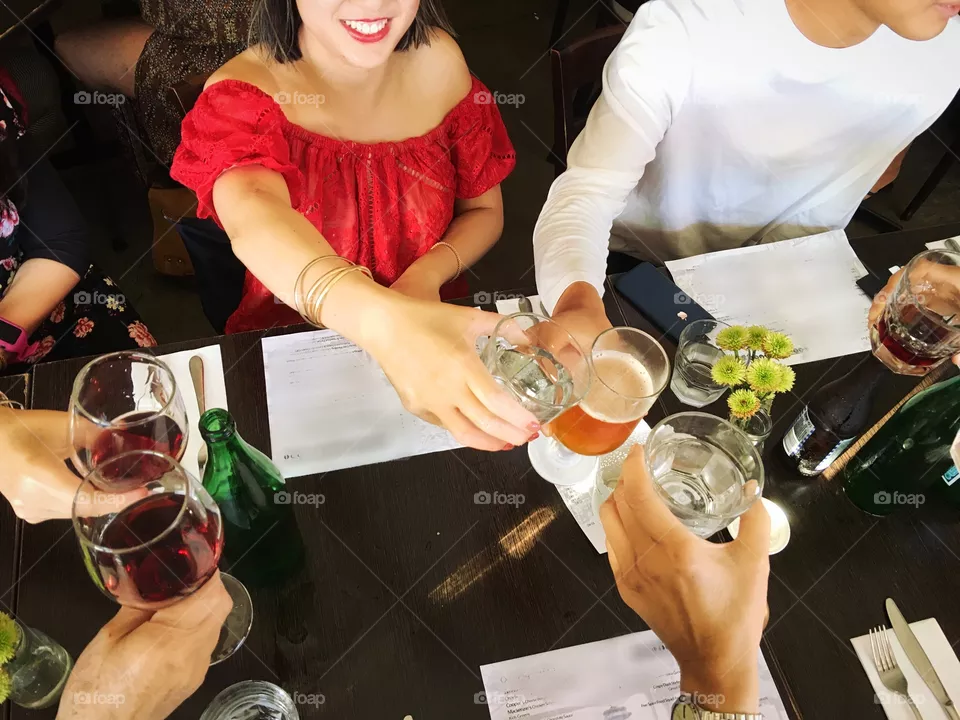 Cheers!! Happy millennial friends holding up their drinks to cheers each other, celebrating a special occasion. 