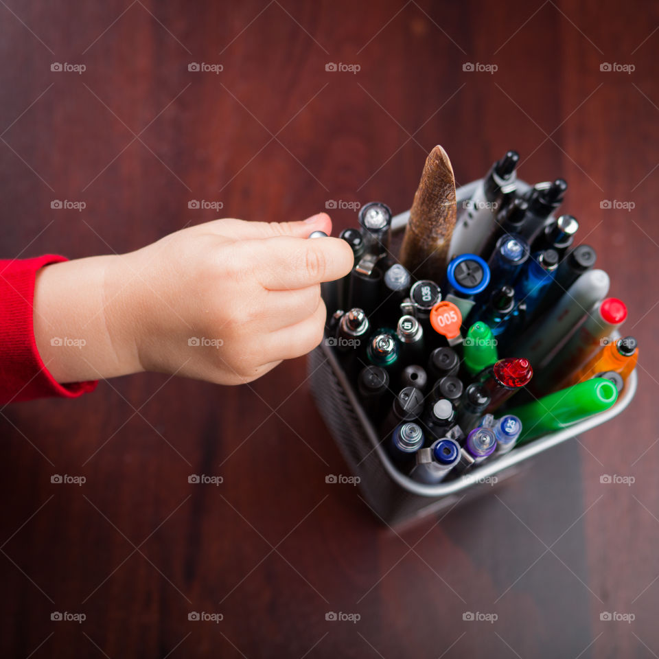 Young hand reaching for pens 