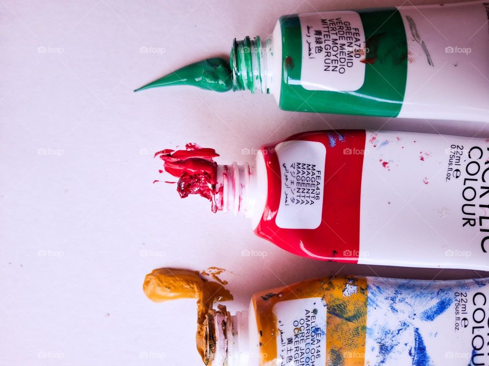 aesthetic photo of empty acrylic paint tubes with colored spots and strokes on paper