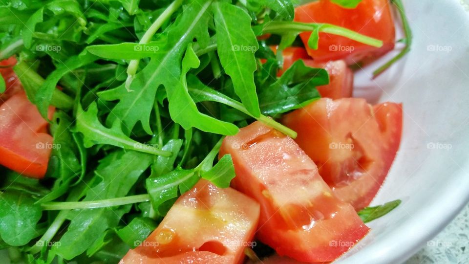 Closeup view of tomato and leafy green salad. A freshly prepared dish with the tomatoes cut into bite sized pieces.