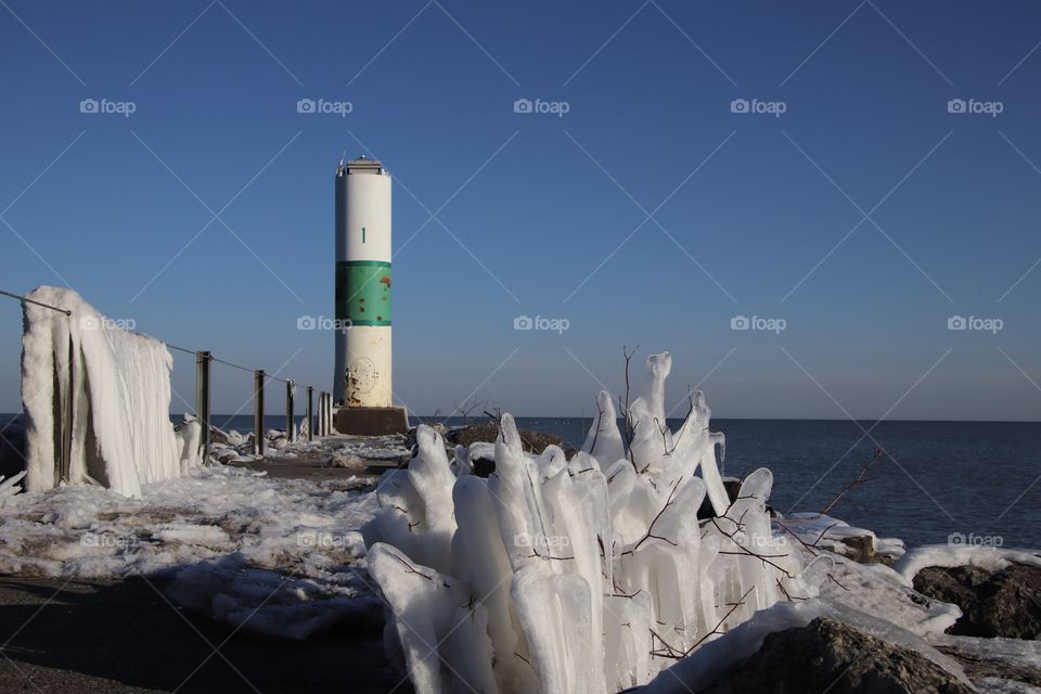 View of Geneva lighthouse in Winter with ice formations on plants along Lake Erie