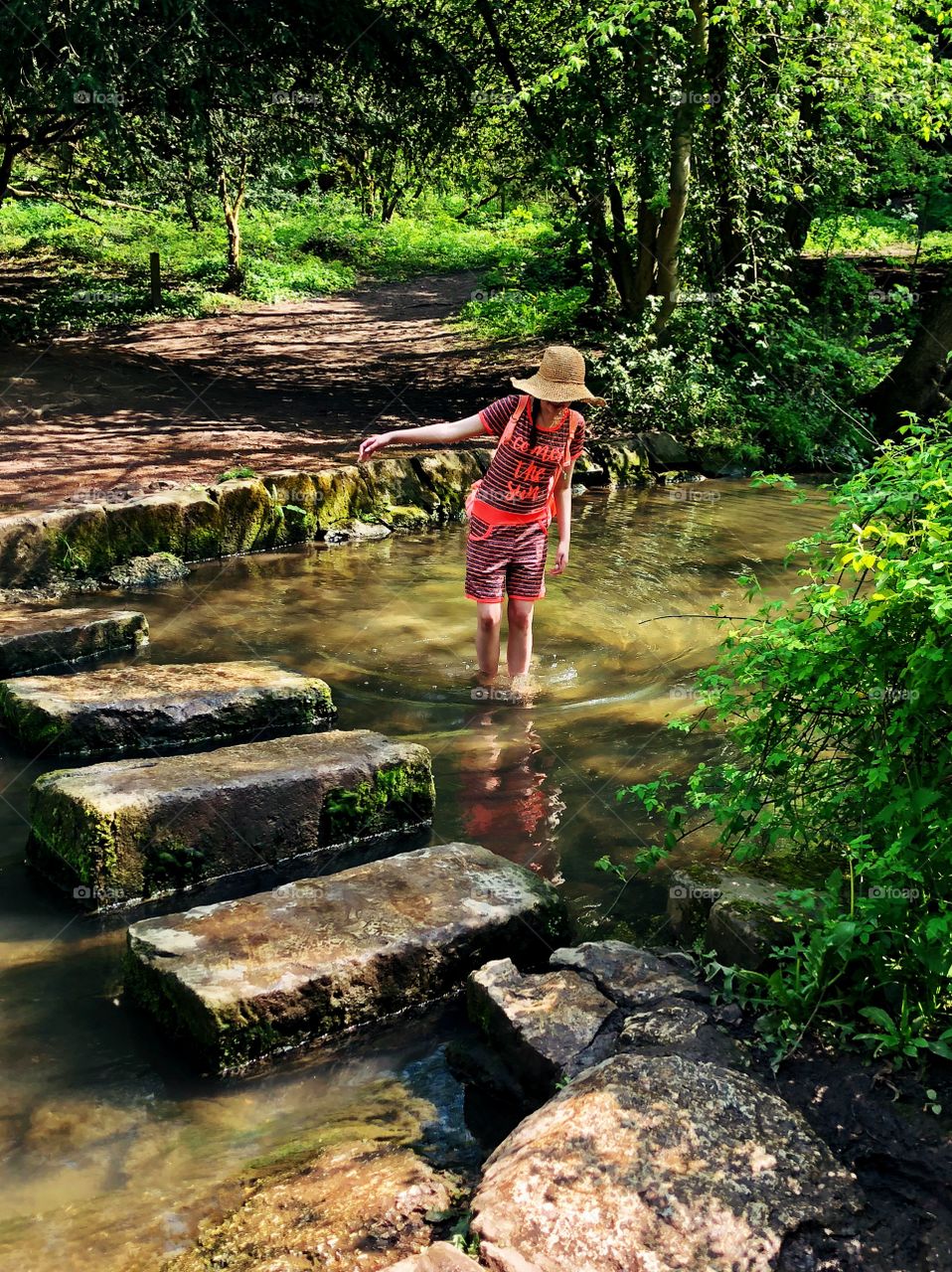 The best things in life are free. Girl enjoying the sunshine whilst paddling in a woodland river. 