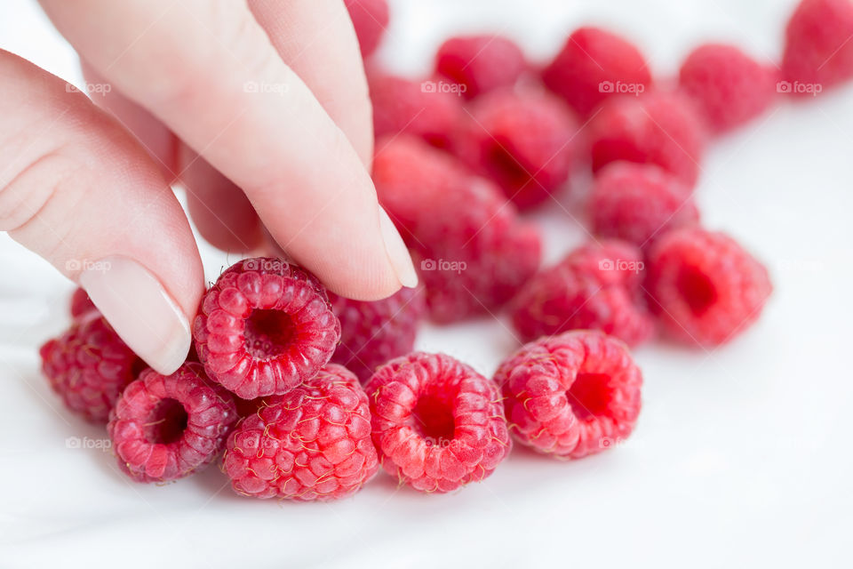 Female hand picking up fresh raspberry, closeup