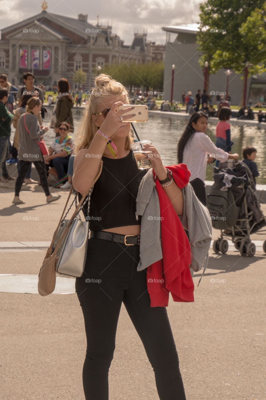 A blond girl using a mobile phone to make a picture