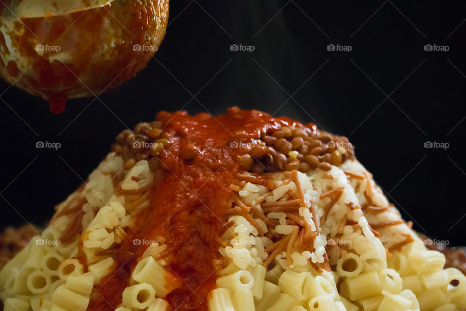 Koshary meal. Typical and cheap Egyptian lunch meal. Covered with red sauce.