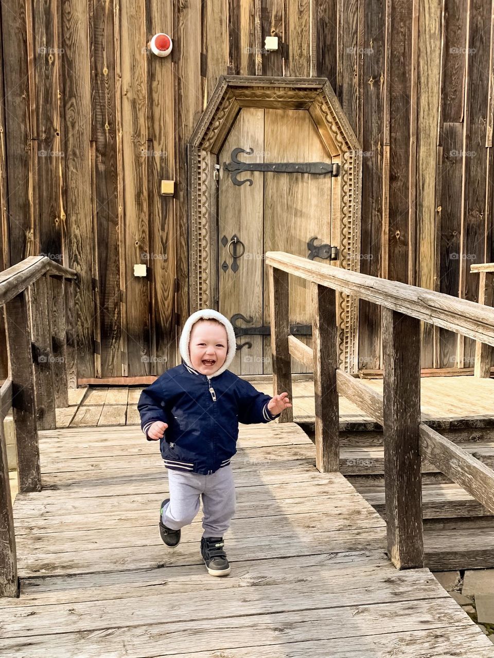 Little boy running and laughing in front of old wooden church, Baturyn, Ukraine 