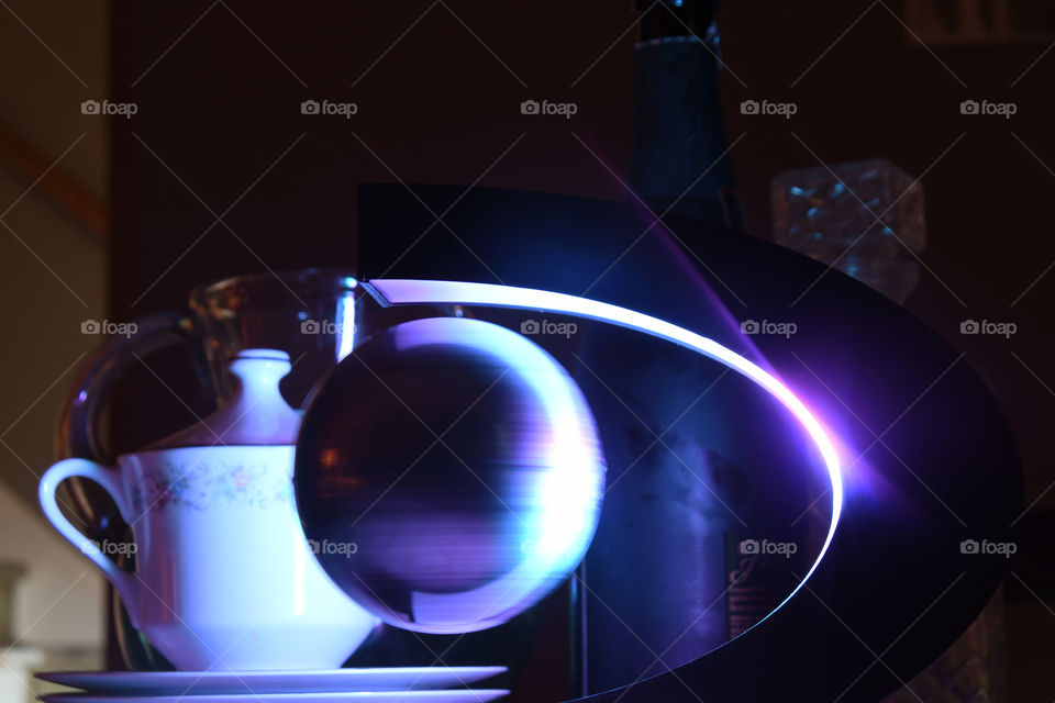 A world globe levitates and spins on a electromagnetic device with funky psychedelic lighting on a kitchen room table.