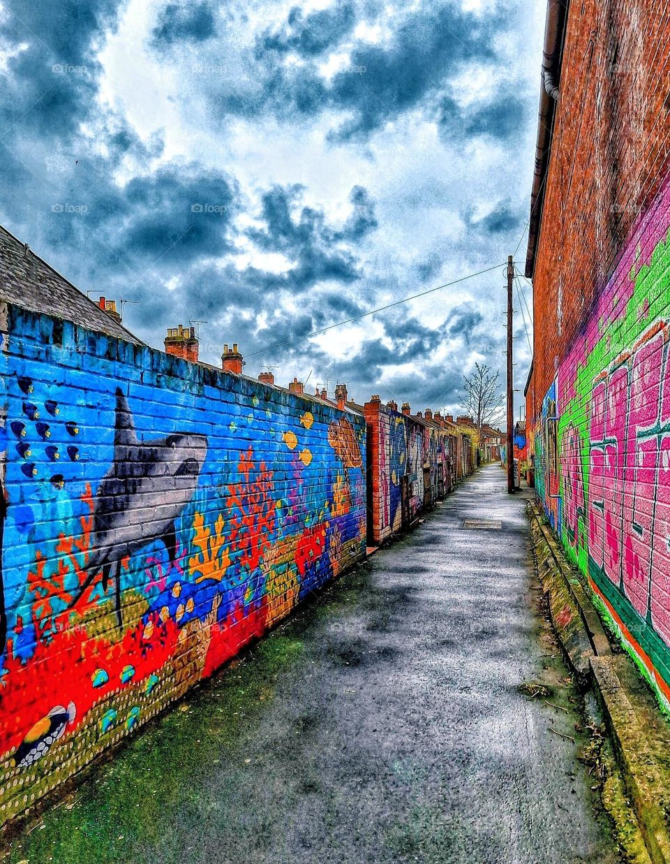 Bright seascape mural in an urban alleyway on a wet stormy day