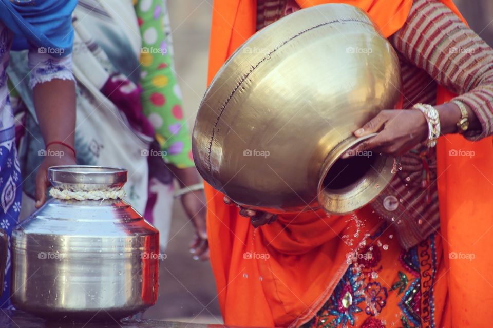 A woman pouring water from a well. 
