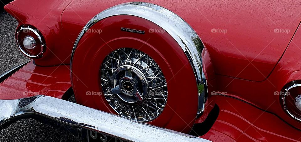 The back of a red Ford Thunderbird showing the spare tyre and the lights at Cherbourg car show