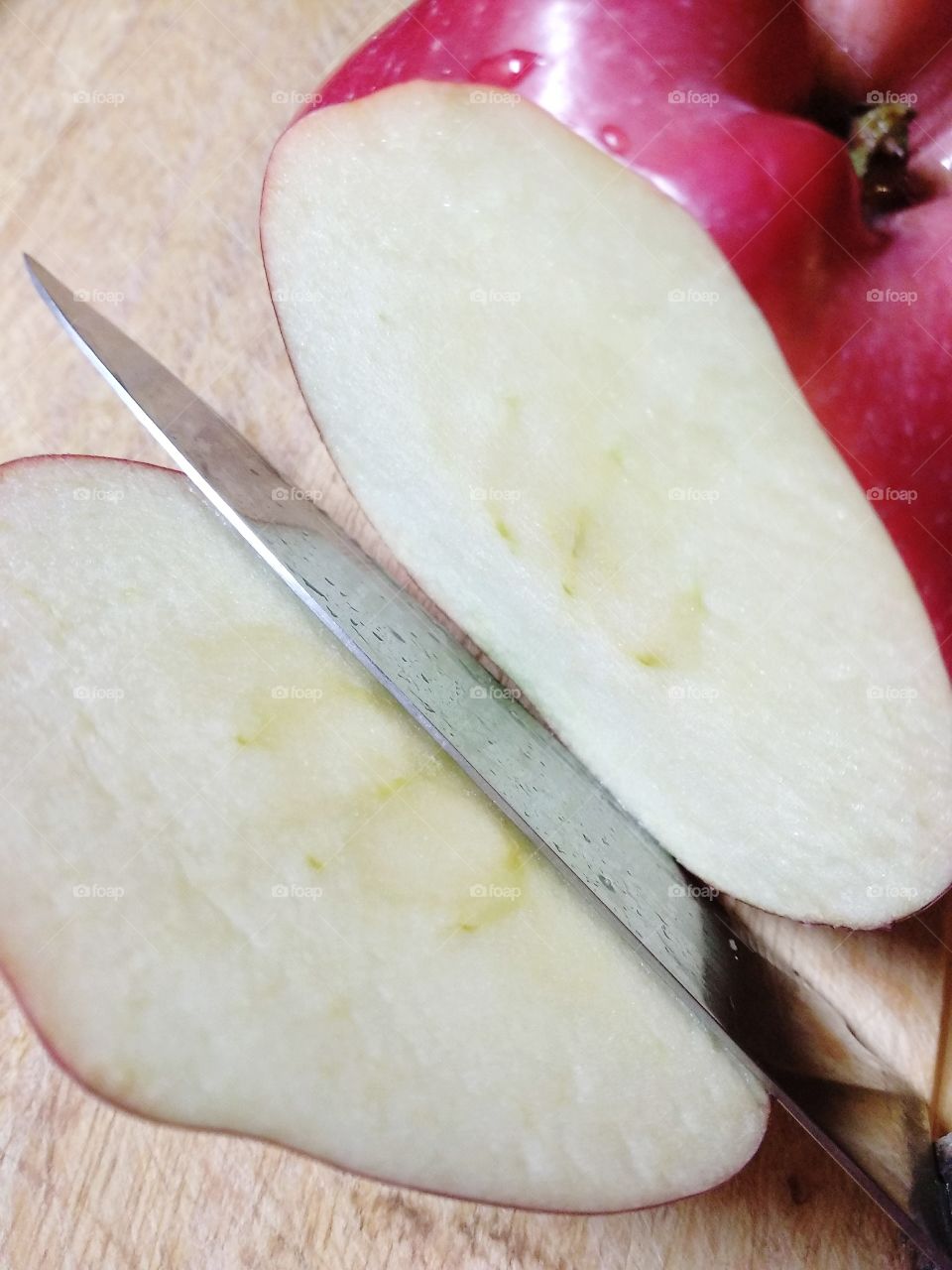 The piece of apple which is cut off by a knife close up
