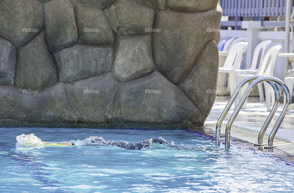 Asian boy holding foam swimming in the pool.