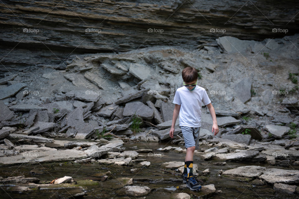 Young boy hiking through a rocky stream outdoors 