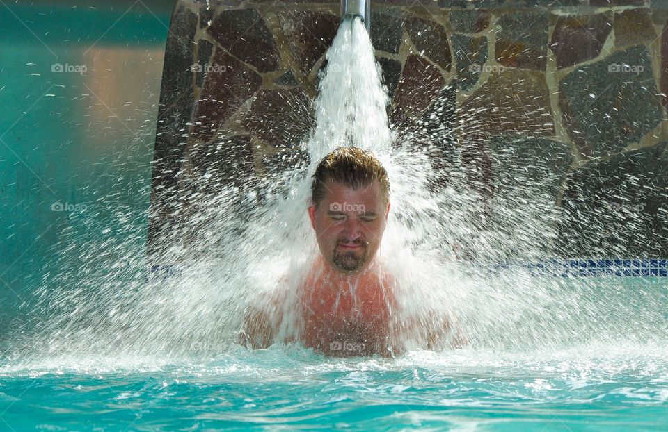 Mature man with eye closed in falling water