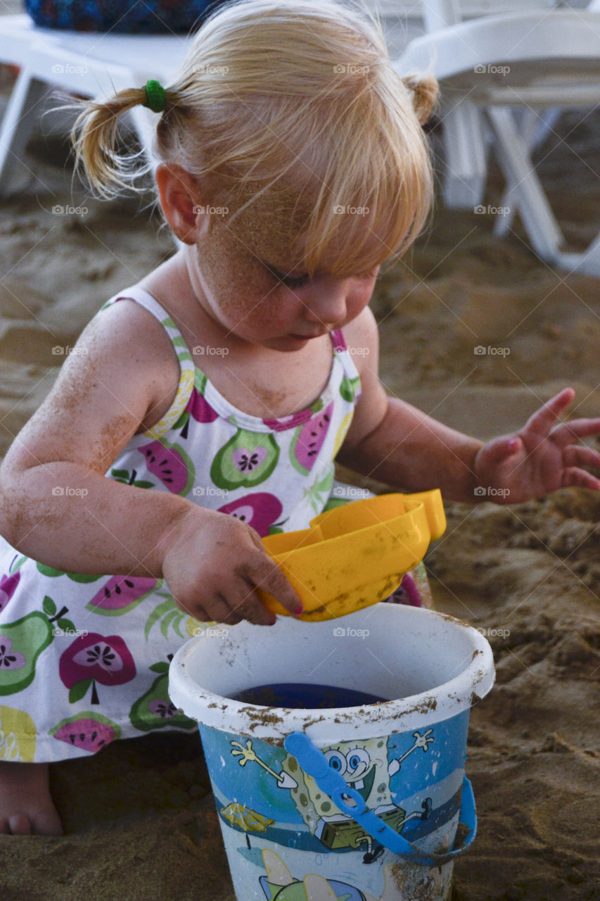 Little two year old Swedish girl playing with her toys on the beach. The girl is on vacation with her parents (photographer) in Antalya, Turkey.