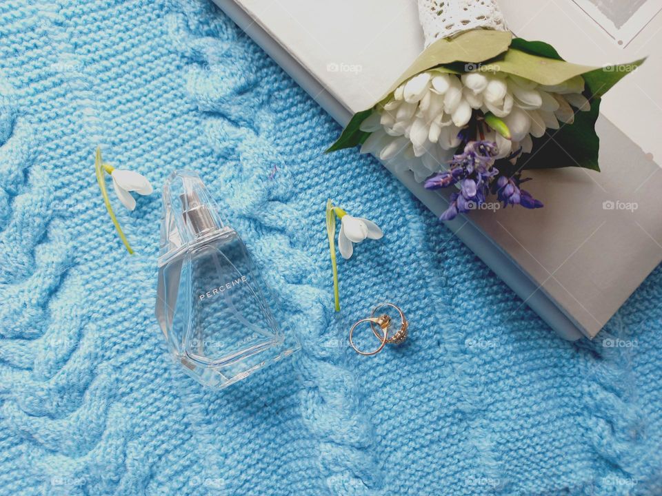 perfume and snowdrops on a blue sweater.