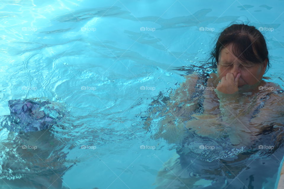 Woman in the swimming pool closing her nose