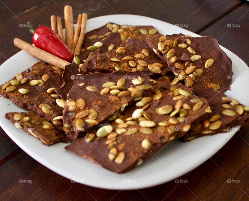 Chocolate with cinnamon sticks and red chili pepper on plate