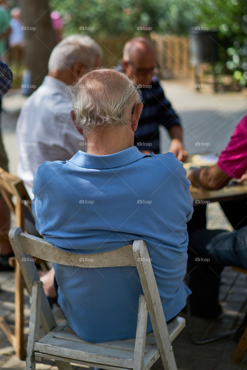 Elderly man sitting in a street dominoes