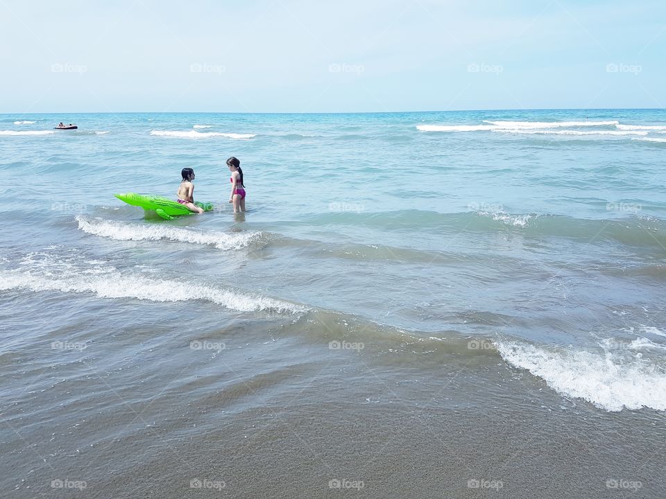 Two little girls playing in the Tuscany sea